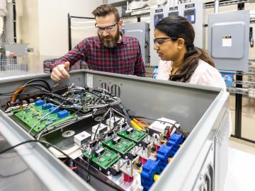 Steven Campbell and Radha Krishna-Moorthy discuss part of the power electronics that make up the Smart Universal Power Electronics Regulator technology developed at ORNL. Credit: Carlos Jones/ORNL, U.S. Dept. of Energy