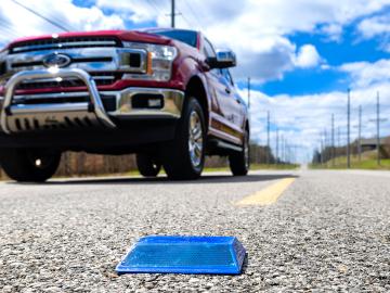 Close up of a reflective road marker as a pickup truck drives past