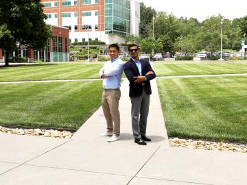 Two researchers standing back to back in a grassy area