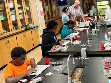 Group of young kids sitting at a lab table.