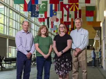  A group of ORNL staff standing in a long corridor with flags hanging from the ceiling