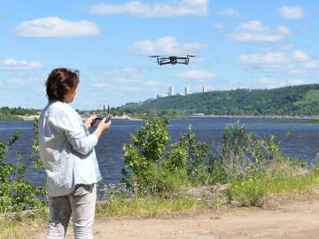 A woman operates a drone near a lake