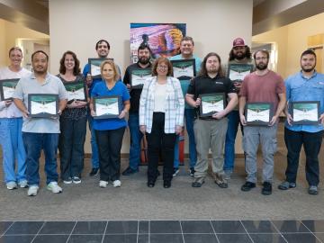 A group photo of technicians and their supervisor after an awards ceremony.