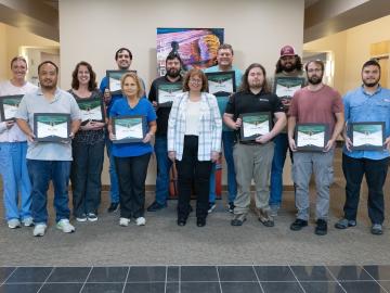 A group photo of technicians and their supervisor after an awards ceremony. 