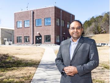 Kashif Nawaz standing in front of a two story brick building that houses active research