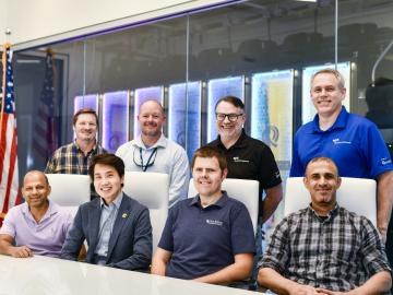 Team of four people seated in front of four people standing in the network operations center at EPB at Chattanooga.