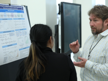 ORNL's Quantum Science Center Director is speaking to a attendee at Purdue University Quantum Science Center Summer School poster presentation