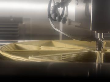 A view inside a JuggerBot 3D printer at the manufacturing demonstration facility. You can see the machine 3D printing material in a wheel format