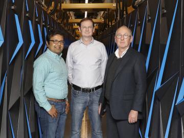 L-R: ORNL’s Arvind Ramanathan, Hugh O’Neill, and Paul Gilna inside the Summit supercomputer room. Photo courtesy: Oak Ridge National Laboratory.