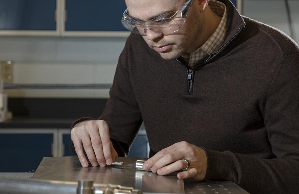 Oak Ridge National Laboratory’s Chris Petrie assembles a fiber optic sensor, fabricated using additive manufacturing, for measuring dimensional changes.