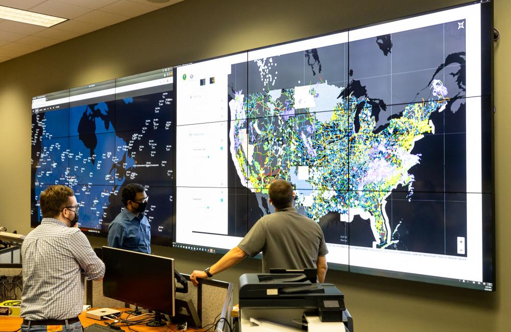 Researchers looking at large screens showing U.S. maps with data