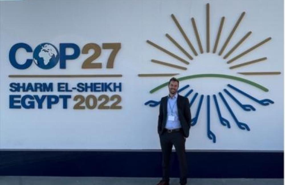 David McCollum standing in front of COP27 sign.