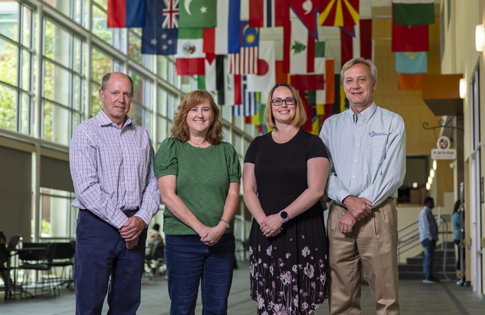 A group of ORNL staff standing in a long corridor with flags hanging from the ceiling