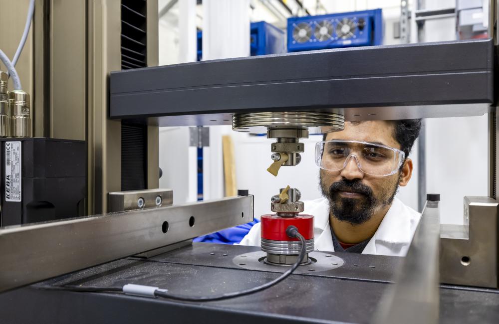 Researcher gazes through a mechanical testing machine for batteries