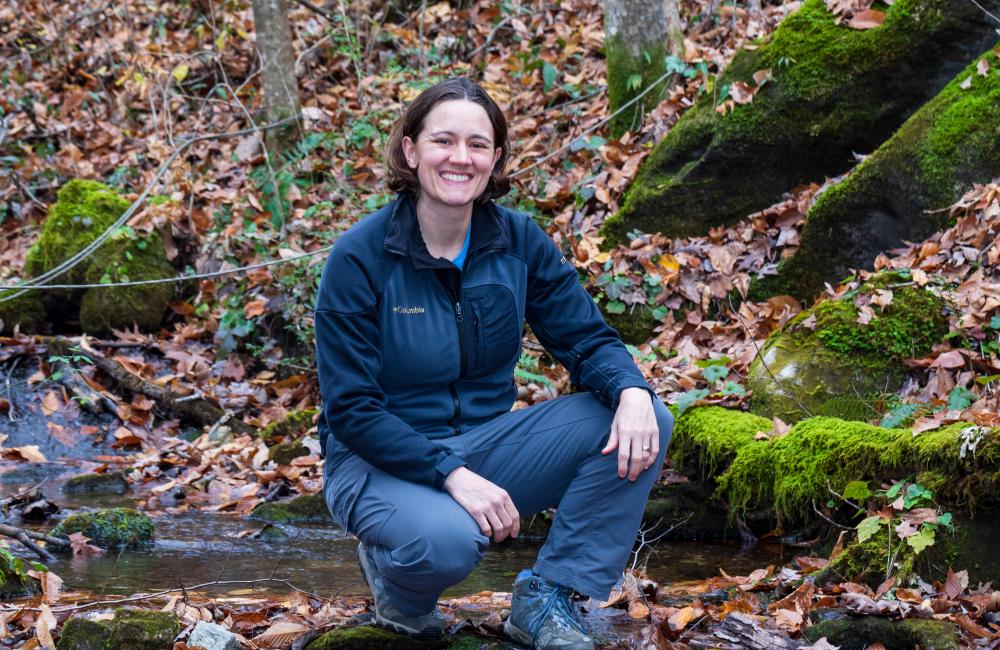 ORNL researcher Natalie Griffiths by a forest stream in the fall