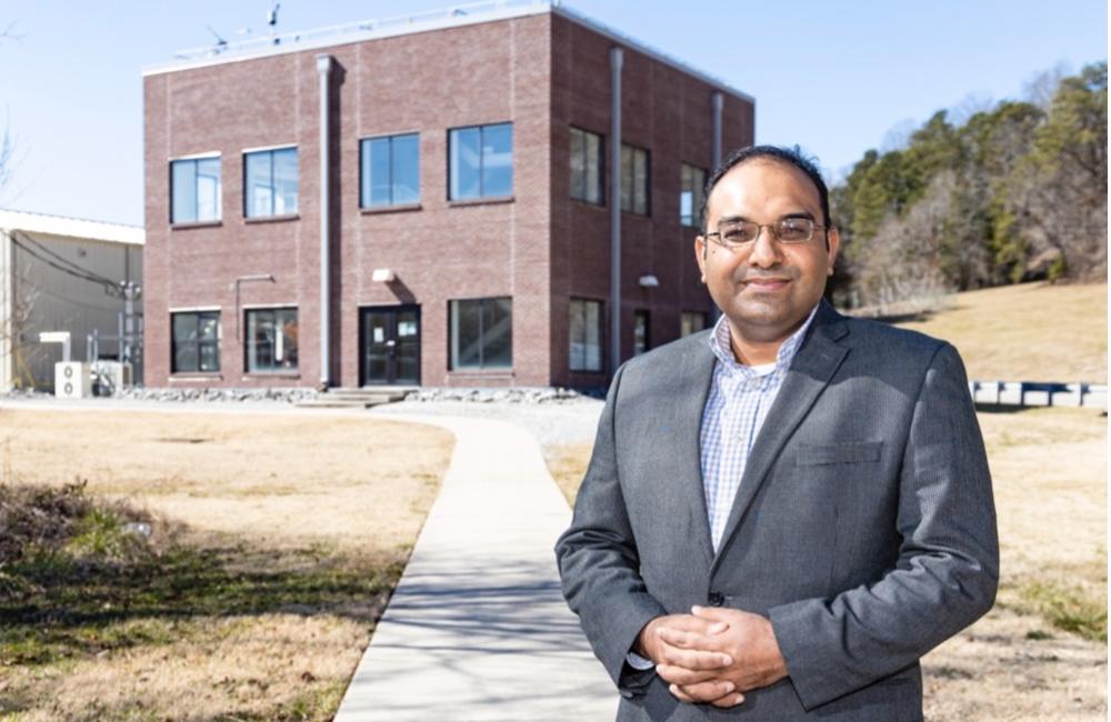 Kashif Nawaz standing in front of a two story brick building that houses active research