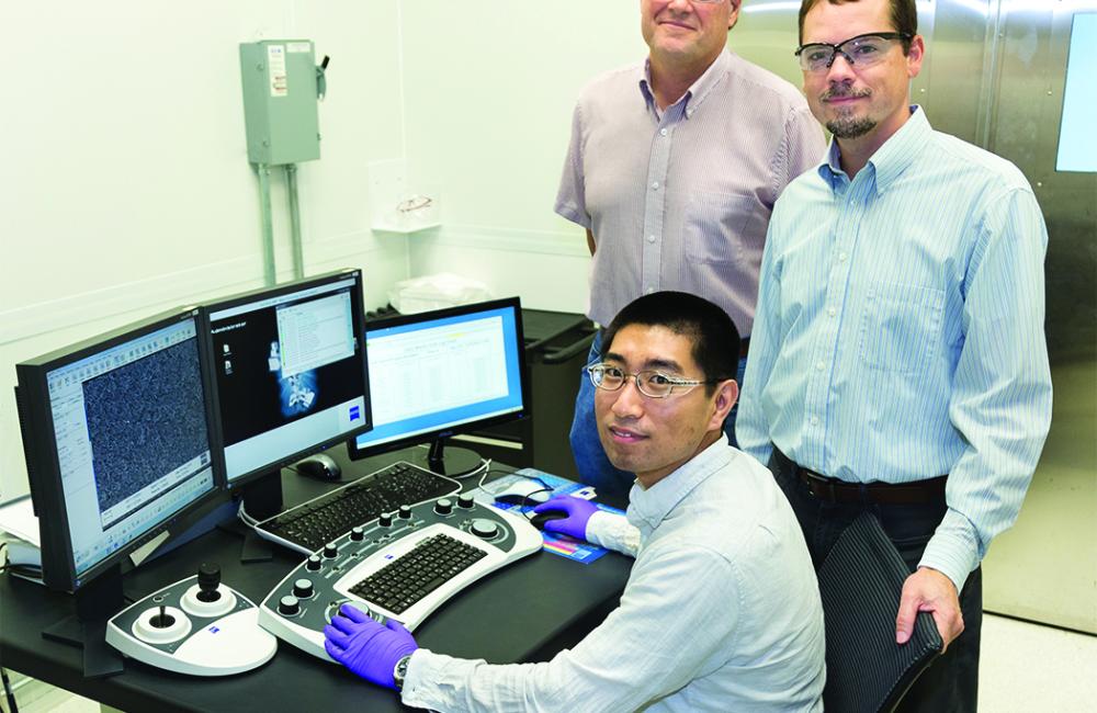 ORNL’s Yang Song, seated, Dale Hensley, standing left, and Adam Rondinone examine a carbon nanospike sample with a scanning electron microscope. (ORNL photo by Genevieve Martin) 