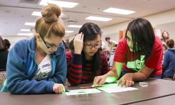 Young women being instructed by an ORNL scientist during a demo